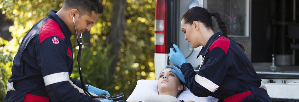 Trustworthy, man and woman professional emergency medical technicians checking a young female patient on a gurney at the back of an ambulance.