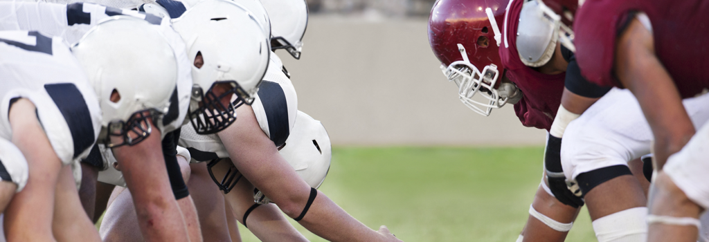 Professional athlete, football players face-off at the line of scrimmage in full gear.