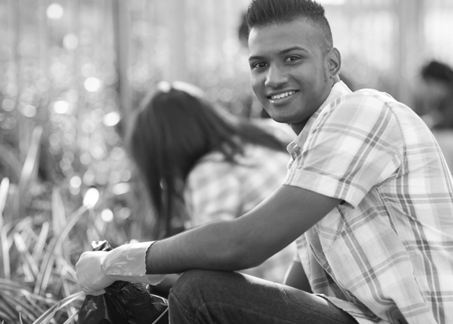 Trusted young male volunteer smiling as he helps cleanup urban garden